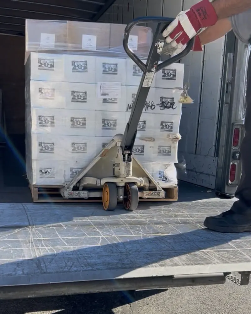 The first pallet of Artisanal Blends by E2 coffee cases being unloaded from a delivery truck with a pallet jack